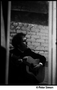 Tim Hardin smoking a cigarette and playing guitar at the Unicorn Coffee House, Boston, Mass.