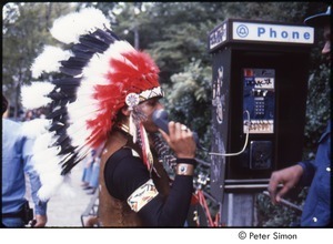 MUSE concert and rally: man in Native American ceremonial dress talking on a payphone