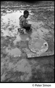 Young boy riding a toy car in the mud, Resurrection City