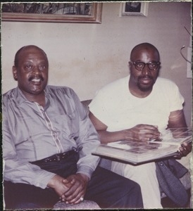 Ben Webster seated with Yusef Lateef, looking at photographs