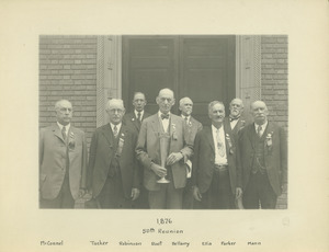 Eight members of the class of 1876 standing in front of Memorial Hall holding a trophy