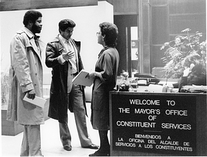 Two unidentified men speaking to an unidentified woman at the entrance to The Mayor's Office of Constituent Services