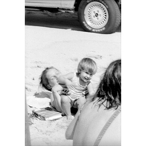 Unidentified toddler with two adults at the beach.