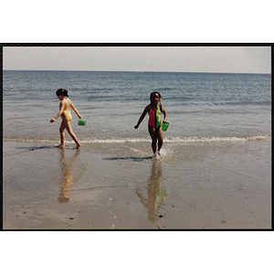 Two girls play on the shoreline at the beach