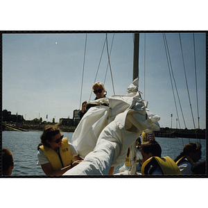 A woman and two children work with the rigging on a sailboat in Boston Harbor