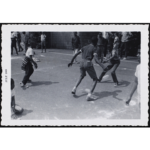 Two boys with balloons fixed to their ankles compete in a game as other boys look on during Tom Sawyer Day