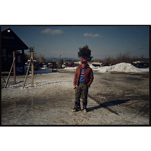 A teenage boy stands in the parking lot of a ski resort