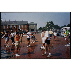 A woman sprays a hose on runners during the Bunker Hill Road Race