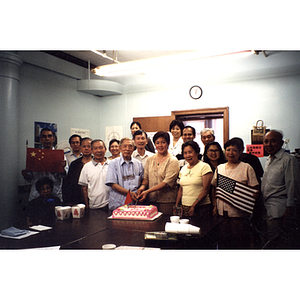 Chinese Progressive Association members gather around a man and women who are cutting cake