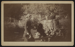 Three-quarter portrait of Lesley Dillingham Bangs, standing, facing right, holding a riding crop and her dog's paw, Winchester, Mass., ca. 1894