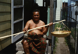 Cambodian basket maker Em Yung at home, holding a bamboo shoot purchased from and import store in New Jersey
