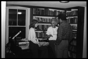 Eugene Terry (center) conversing with unidentified woman and Richard Hall in front of bookshelves, at the book party for Robert H. Abel