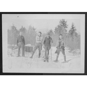 Young men standing outside wearing skis and snowshoes