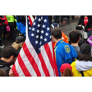 American flag waves next to spectators at One Run finish line