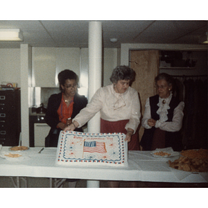 A woman holds up a 4th of July cake decorated with an American flag
