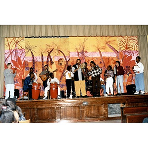 A band composed of Inquilinos Boricuas en Acción musicians and school children making music on a school stage.