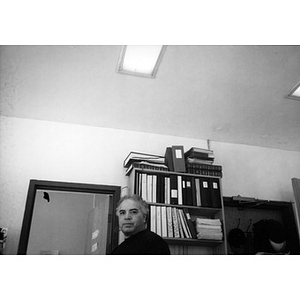 Inquilinos Boricuas en Acción employee standing in front of a bookshelf full of binders and stacks of papers.