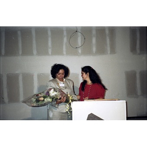 Clara Garcia presents flowers to Jovita Fontanez at Taino Tower ribbon cutting ceremony.