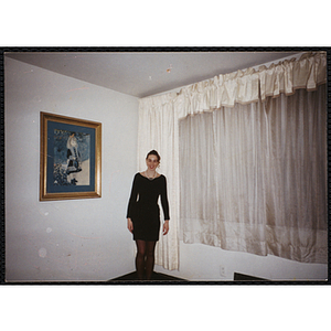 A young woman in a black dress standing at the corner of a room with a painting on the wall during a Boys & Girls Club event