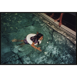A girl in a flotation ring swims in a natorium pool