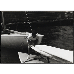 A Youth assisting with the sail on the deck of a sailboat