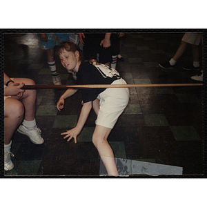 A Girl ducking under a limbo stick