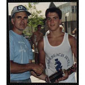 A man and a teenage boy shake hands and pose with a trophy during the Battle of Bunker Hill Road Race