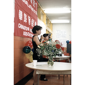 Two women address a group of people gathered for a Chinese Resident Association celebration