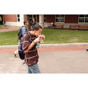 Odalis David Polanco eats a sandwich as he walks through Centennial Circle