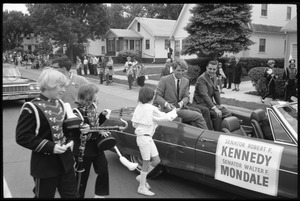 Robert F. Kennedy shaking hands with an admirer while riding in a convertible down the streets of Worthington during the Turkey Day festivities