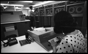 Woman entering data into a console as a man loads a tape on a Honeywell Model 400 mainframe computer
