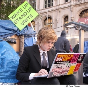 Occupy Wall Street: demonstrator in a suit using a bumper sticker-covered laptop