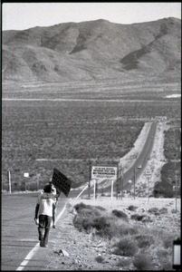 Activist on the road near the entrance to the Nevada Test Site holding a sign reading 'Stop nuclear weapons testing': Nevada Test Site peace encampment