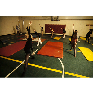 Women stretching beside mats in a gym