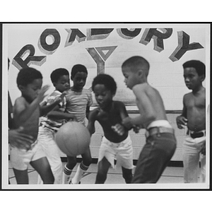 Young boys play basketball in front of Roxbury YMCA sign