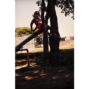 Boy seated on seesaw at a playground