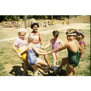 Children in swimsuits smiling and holding hands in a park