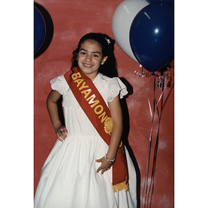 A girl wearing a Bayamon sash poses with a smile at the Festival Puertorriqueño