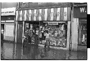 Floods in Market St., Downpatrick. Local man lies in the water wearing a frogman's suit