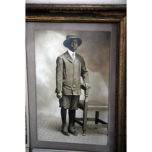 A young African American man posing beside a chair