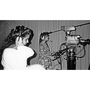 Two girls operating video recording equipment.