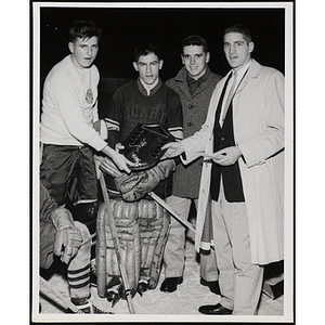Four men posing on the ice with a plaque at the Boys' Clubs of Boston Hockey League Championship