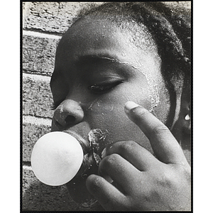 Close-up of an African American girl from the Roxbury Boys' Club blowing a bubble with gum