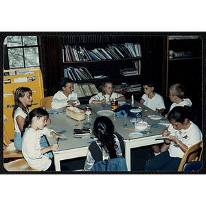 A group of six girls and two boys sitting around a table, working on projects for their arts and crafts class at the Charlestown Boys and Girls Club