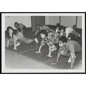 Children perform stretches on mats