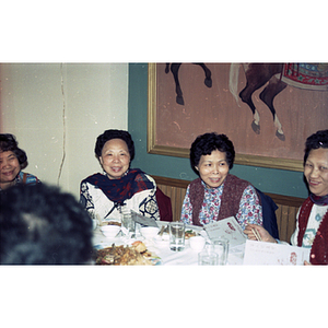 Women smile and chat while eating at a restaurant table during a Chinese New Year celebration hosted by the Chinese Progressive Association