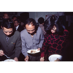 Men and a woman serve themselves dinner during an International Women's Day celebration