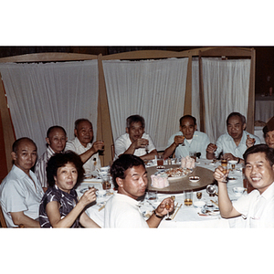 Association members sit around a dinner table at a restaurant in Guangzhou, China and raise their glasses