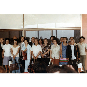 Men and women stand against a wall of windows