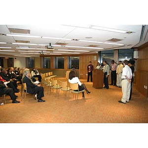 Odalis David Polanco speaks in front of an audience while the Torch Scholars stand behind him